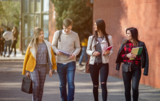 4 college age International Students Walking outside with backpacks and school supplies