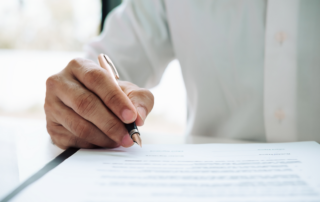 Generic blog image. Closeup photo of man's hand holding a pen. White button down shirt.